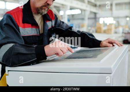 Close-up of foreman in uniform working on computer of machine in the factory Stock Photo