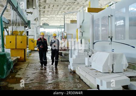 Couple of engineers using tablet pc while walking along the workshop and controlling the process of production Stock Photo