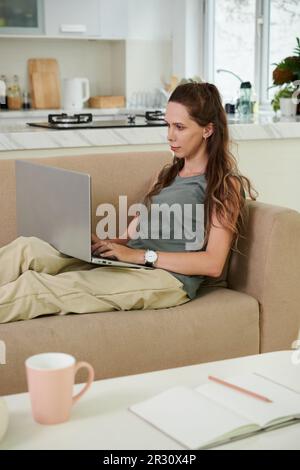 Young businesswoman working from home, answering e-mails from colleagues Stock Photo