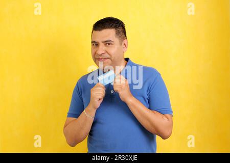 Forty-year-old dark-skinned Latino adult man shows his credit card to make payments, online purchases for months without interest Stock Photo