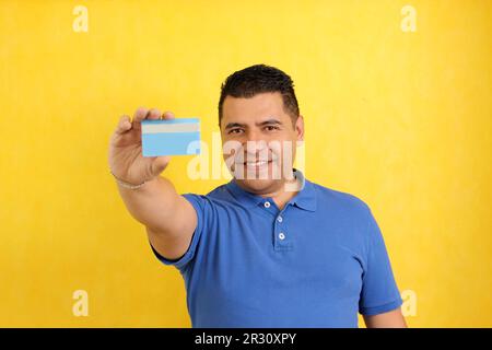 Forty-year-old dark-skinned Latino adult man shows his credit card to make payments, online purchases for months without interest Stock Photo
