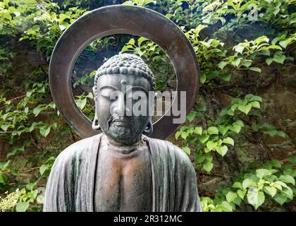 A Buddha type sculpture at Samares Manor botanic garden in St Clements, Jersey, Channel Islands. Stock Photo