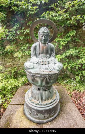 A Buddha type sculpture at Samares Manor botanic garden in St Clements, Jersey, Channel Islands. Stock Photo