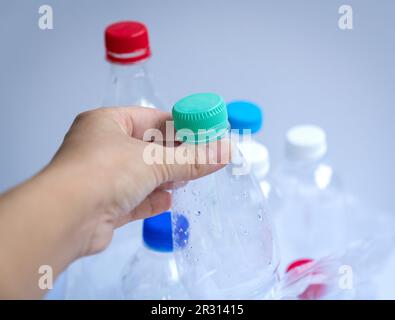 Hand putting a plastic bottle inside a plastic bag filled with bottles. Recycle or trash concept. Stock Photo