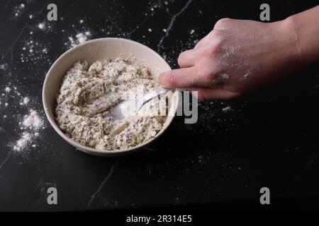 photo a mixture of cottage cheese, flour and sugar eggs, a man stirs with a fork Stock Photo