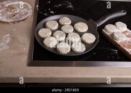 photo cheesecakes frying in a pan on the stove in the kitchen Stock Photo