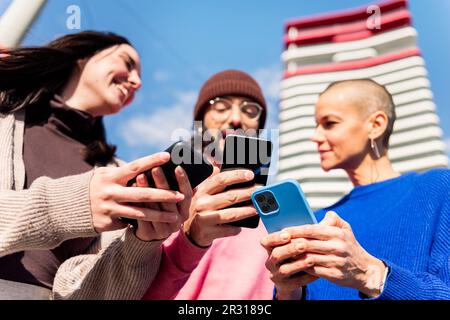 three young friends having fun using mobile phones Stock Photo