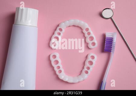 Bite correction. Toothpaste, brush, dentist mirror and dental mouth guards on pink background, flat lay Stock Photo