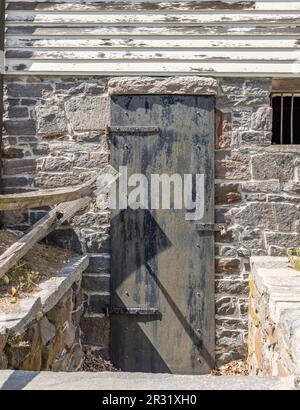 Old black metal door on the basement level of a sag harbor home Stock Photo