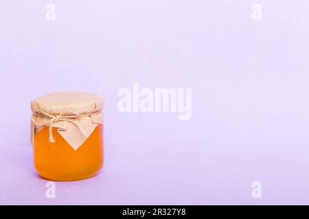 Glass jar full of honey on a colored background. Honey Bottle Mock-Up. Stock Photo
