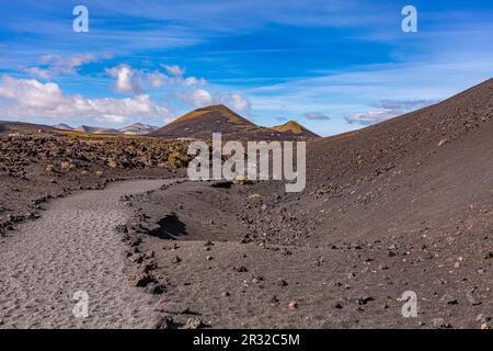 Winding road leading to mountains. Sandy-clay soil. Mountain landscape under white clouds. Stock Photo