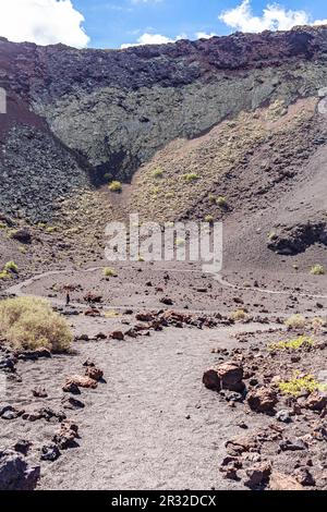 Winding road leading to mountains. Sandy-clay soil. Mountain landscape under white clouds. Stock Photo