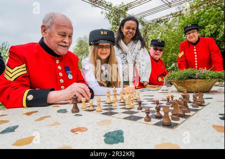 London, UK. 22nd May, 2023. The London Square Community Garden, Sanctuary Garden, Chelsea Pensioners playing on the garden chess boards and trying out the swing seat, enjoying the communal spirit with volunteers from the roof garden on a high- rise estate in Battersea which inspired the design. Monday at the 2023 Chelsea Flower Show. Credit: Guy Bell/Alamy Live News Stock Photo