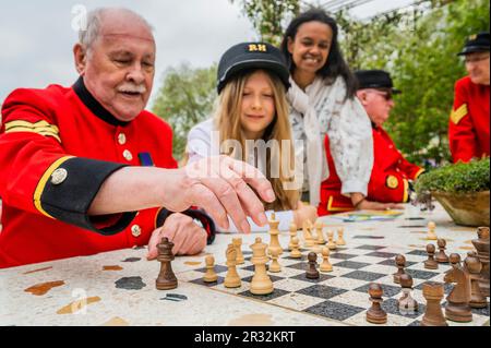 London, UK. 22nd May, 2023. The London Square Community Garden, Sanctuary Garden, Chelsea Pensioners playing on the garden chess boards and trying out the swing seat, enjoying the communal spirit with volunteers from the roof garden on a high- rise estate in Battersea which inspired the design. Monday at the 2023 Chelsea Flower Show. Credit: Guy Bell/Alamy Live News Stock Photo