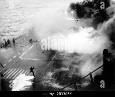 The crew of the U.S. Navy aircraft carrier USS Saratoga (CV-3) fighting fires after a kamikaze hit the forward elevator on 14 May 1945. When Japan was facing defeat in late 1944 it chose to destroy US ships with suicide bombings, known as Kamikaze.These attacks were a potent physical and psychological weapon and sunk a total of 47 ships at a cost of more than 3000 pilots and planes. By late 1944 the US Navy was large enough that the losses were insignificant and they did not alter the course of the war. Stock Photo
