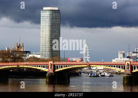 Millbank Tower, London Eye / Millennium Wheel and red London bus crossing New Vauxhall Bridge across the River Thames under a stormy sky, London, UK Stock Photo