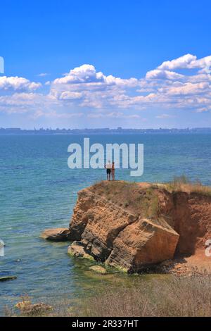 The photo was taken on the Black Sea coast near the city of Odessa. The picture shows a young couple admiring the sea standing on a sandstone cliff. Stock Photo