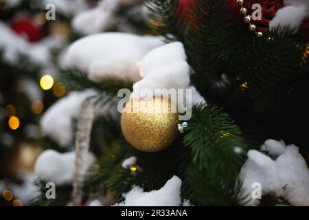 beautiful multi-colored toys on a Christmas tree against the background of lights and snow Stock Photo