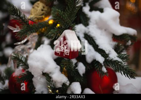 beautiful multi-colored toys on a Christmas tree against the background of lights and snow Stock Photo