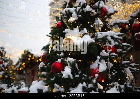 beautiful multi-colored toys on a Christmas tree against the background of lights and snow Stock Photo