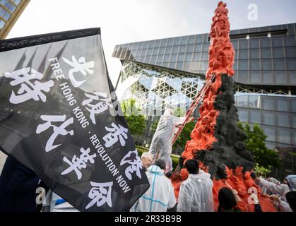 Berlin, Germany. 22nd May, 2023. A flag with the inscription 'Free Hong Kong - Revolution Now' is held high during the painting action in front of the 'Pillar of Shame' memorial. The memorial commemorates the victims of the violent suppression of the Chinese protest movement on Tiananmen Square in Beijing in June 1989. Credit: Hannes P Albert/dpa/Alamy Live News Stock Photo