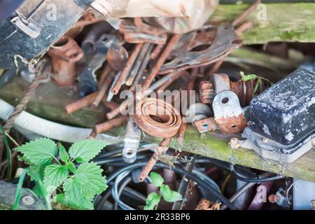 Scrap metal piled up on the old wooden table outdoors. Rusty objects and tools. Stock Photo