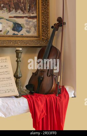 Violin leaning against the wall under the painting Stock Photo
