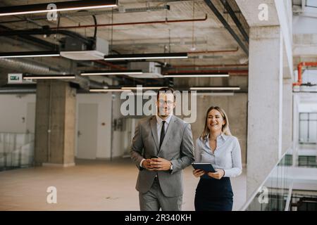 Young coworkers walking and talking along corridor in the modern office Stock Photo
