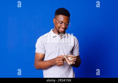 Young good looking African man counting cash and smiling Stock Photo