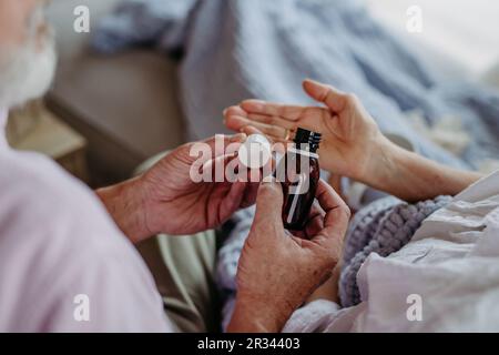Close up of senior man giving medicines to his ill wife. Stock Photo