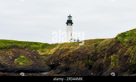 Newport, OR  USA - 3 JUL 2022: Yaquina Head Lighthouse stands tall above the ocean cliffs on overcast day Stock Photo