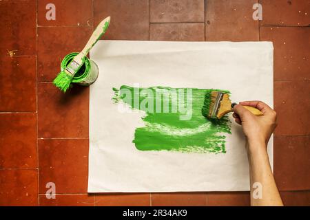 Painting a ream of paper with a pot of green synthetic enamel paint with various brushes Stock Photo