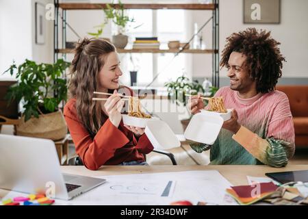 Young colleagues having lunch time in their office. Stock Photo