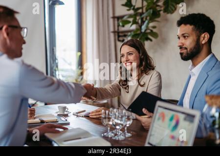 Close up of businesmans shaking hands in office. Stock Photo
