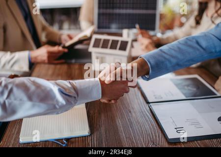 Close up of businesmans shaking hands in office. Stock Photo