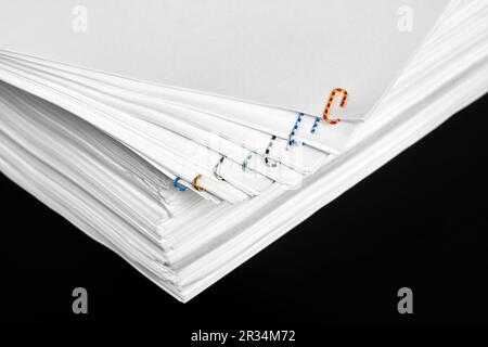 Stacks of papers with multicolored paper clips on a dark background Stock Photo