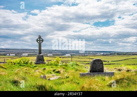 Graveyard with celtic cross in Inis Mór, or Inishmore, the largest of the Aran Islands in Galway Bay, off the west coast of Ireland. Stock Photo