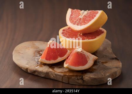 Sliced grapefruit on wood board closeup, shallow focus Stock Photo