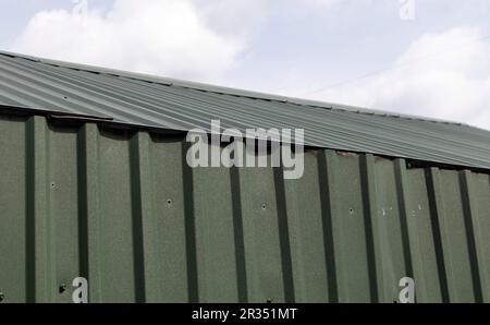 Roofing from a metal profile. Metal roof structure. Textured green metal roof. Corrugated lining. Stock Photo