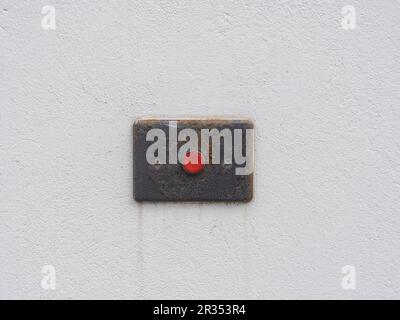 Red old alarm button on the white cement wall. Service accessible entrance sign. Help call button for people Stock Photo