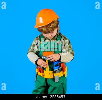 Little kid repairman with toolbelt. Tools for building. Builder boy in safety helmet and toy tools for repair. Little child in builder's uniform with Stock Photo