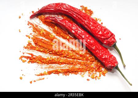 Ground pepper and red hot chili peppers scattered on a white background Stock Photo