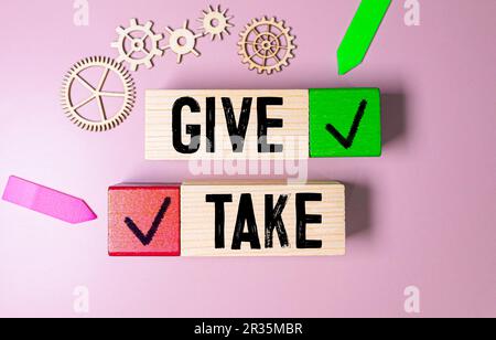 Hand writing the word Give in chalk on a used blackboard. Giving takes many forms and may involve time or money or just our presence and kind words. Stock Photo