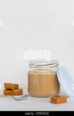 Cooked caramel pudding in a jar with a lid and a spoon Stock Photo