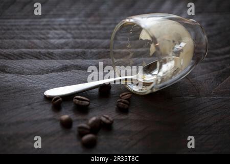 An empty espresso glass with a spoon and coffee beans on a wooden table Stock Photo