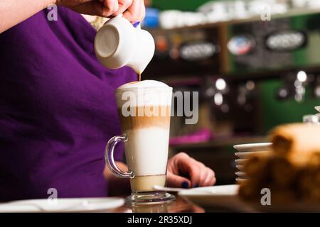 latte macchiato, pouring espresso in glass, pitcher with coffee, milk foam,  energy and caffeine Stock Photo by LightFieldStudios