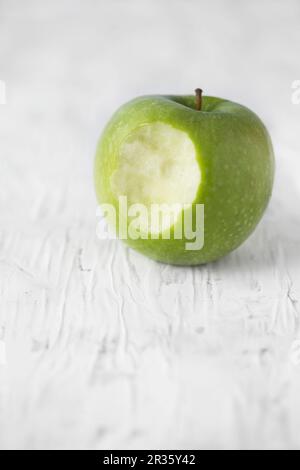 A Granny Smith apple with a bite taken out Stock Photo