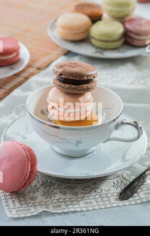Macaroons in a tea cup and on a plate Stock Photo