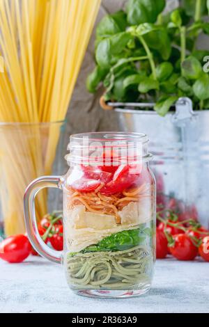 Colourful spaghetti with tomatoes, basil and cheese in a glass Stock Photo