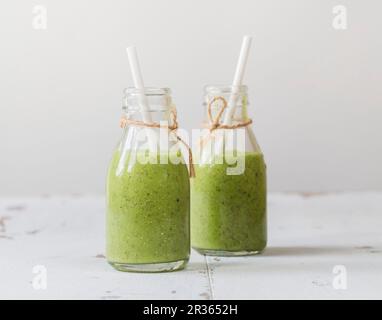 Green smoothies with avocado, kiwi, spinach, ginger and chia seeds in bottles Stock Photo